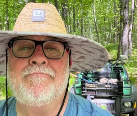eric standing in front of an atv in a forest